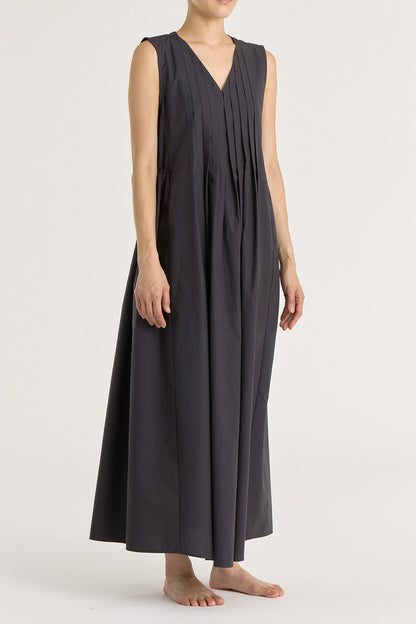 A model wearing a black pleated V-neck dress with side seam pockets and an adjustable drawstring at the back.