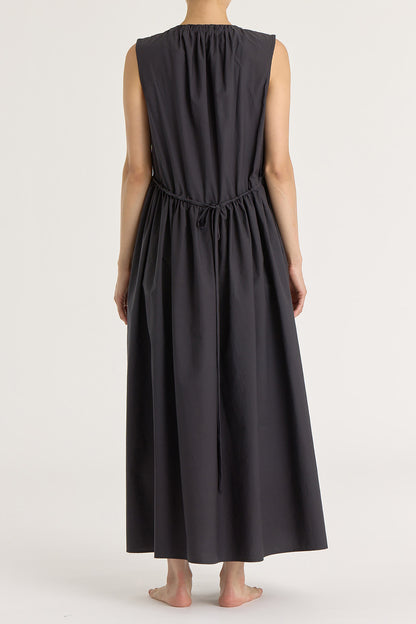 A model wearing a black pleated V-neck dress with side seam pockets and an adjustable drawstring at the back.