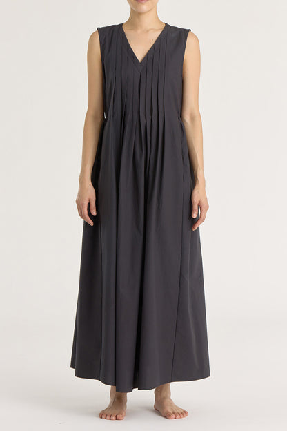 A model wearing a black pleated V-neck dress with side seam pockets and an adjustable drawstring at the back.