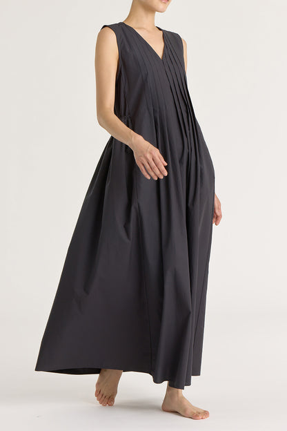 A model wearing a black pleated V-neck dress with side seam pockets and an adjustable drawstring at the back.