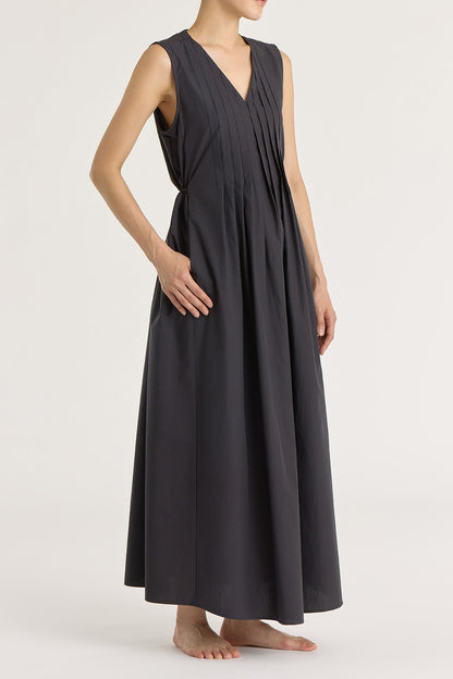 A model wearing a black pleated V-neck dress with side seam pockets and an adjustable drawstring at the back.