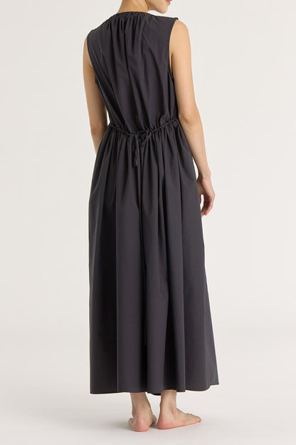A model wearing a black pleated V-neck dress with side seam pockets and an adjustable drawstring at the back.