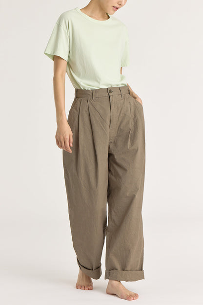 A person wearing a mint green basic crew neck t-shirt with short sleeves, paired with high-waisted trousers.