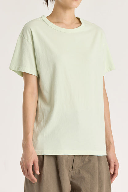 A person wearing a mint green basic crew neck t-shirt with short sleeves, paired with high-waisted trousers.