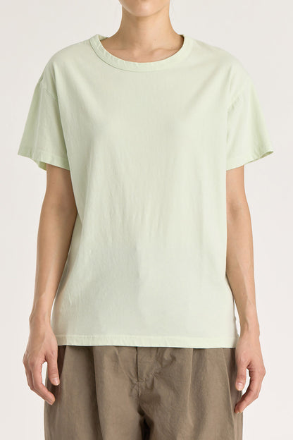 A person wearing a mint green basic crew neck t-shirt with short sleeves, paired with high-waisted trousers.