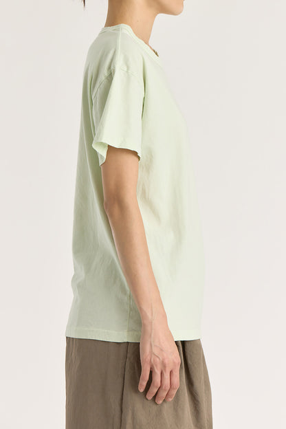 A person wearing a mint green basic crew neck t-shirt with short sleeves, paired with high-waisted trousers.