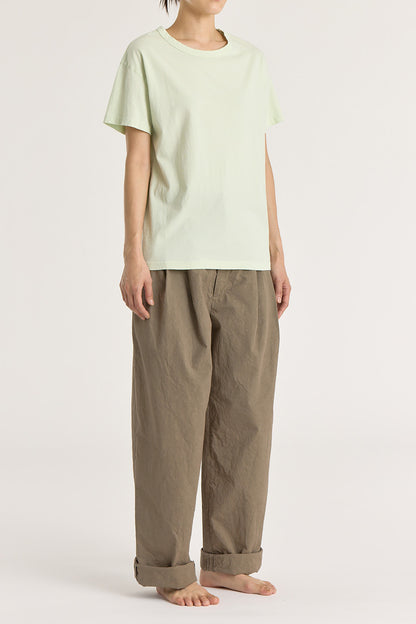 A person wearing a mint green basic crew neck t-shirt with short sleeves, paired with high-waisted trousers.