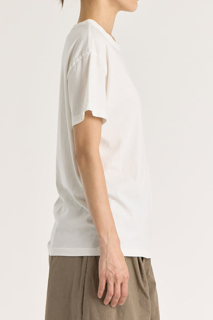 A person wearing a white regular short sleeve tee and brown pants. The tee has a crew neck and short sleeves.