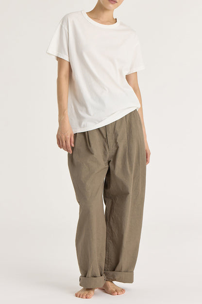 A person wearing a white regular short sleeve tee and brown pants. The tee has a crew neck and short sleeves.
