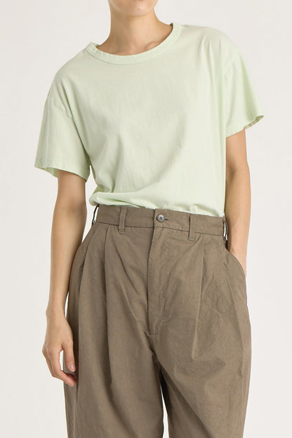 A person wearing a mint green basic crew neck t-shirt with short sleeves, paired with high-waisted trousers.