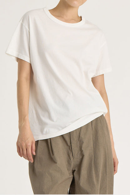 A person wearing a white regular short sleeve tee and brown pants. The tee has a crew neck and short sleeves.